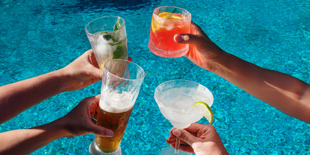 VIETRI Superglass shatterproof drinkware filled with colorful cocktails and drinks beside a swimming pool.