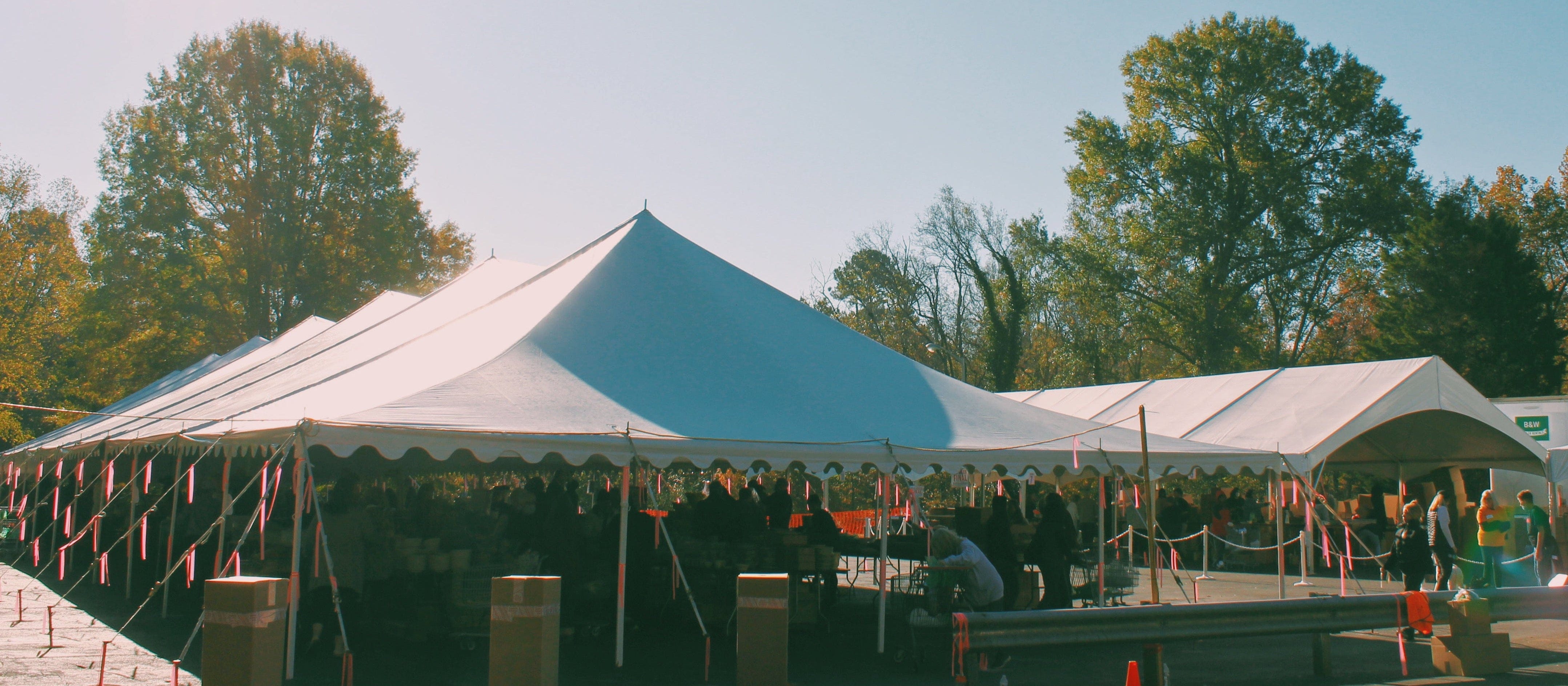 Row of white tents set up outdoors with trees in the background