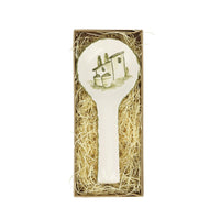 Decorative rest spoon with a house design in a box filled with straw