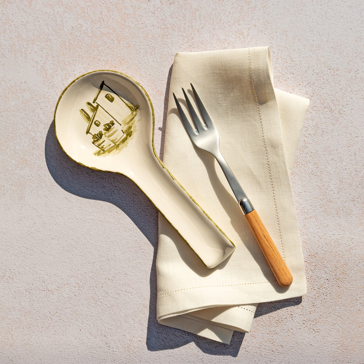 Spoon rest, fork, and folded napkin on a textured surface