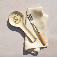 Spoon rest, fork, and folded napkin on a textured surface